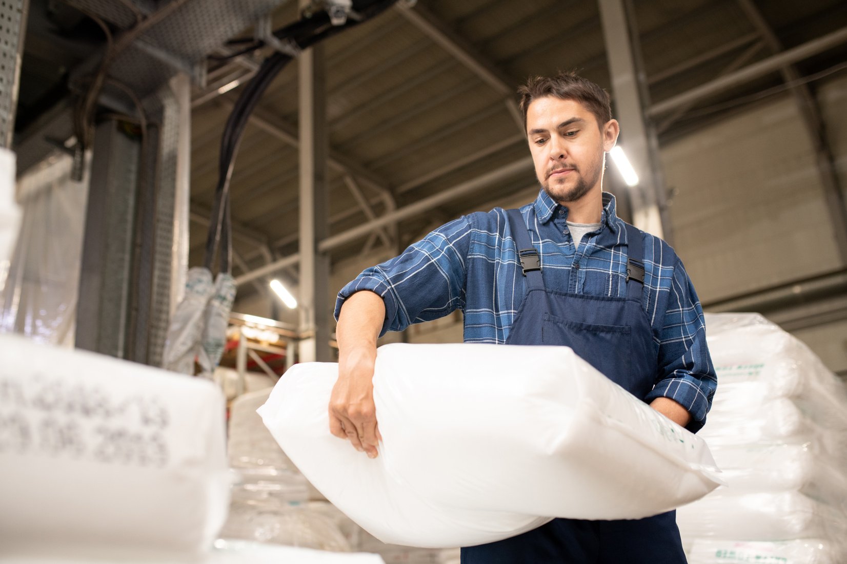 Young Man in Workwear Carrying Heavy White Sack  